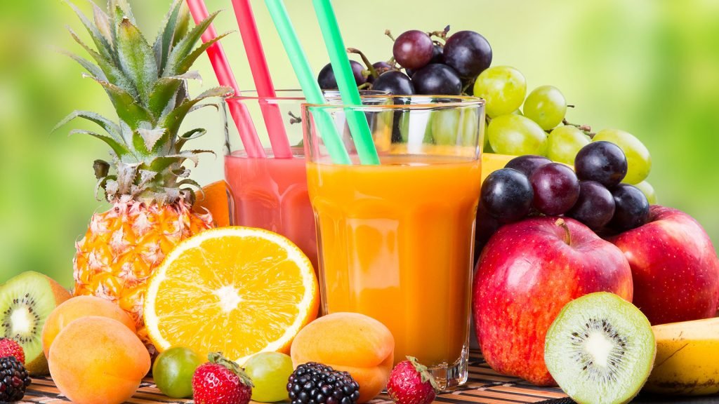 Świeże soki owocowe ze słomkami otoczone owocami: ananas, pomarańcza, winogrona, jabłko, kiwi